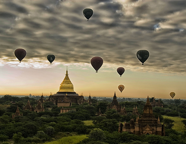 Hot air balloons floating over ancient temples during sunrise in Bagan, Myanmar.