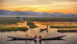 Traditional fishermen on Inle Lake at sunrise, showcasing Myanmar photography and culture tours with unique fishing techniques, serene floating gardens, and breathtaking mountain landscapes