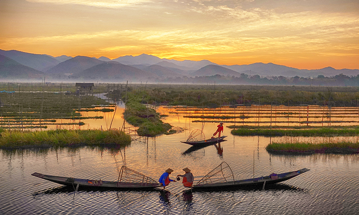 Traditional fishermen on Inle Lake at sunrise, showcasing Myanmar photography and culture tours with unique fishing techniques, serene floating gardens, and breathtaking mountain landscapes