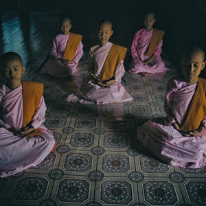 Young Buddhist nuns meditating in a serene setting in Sagaing, Myanmar